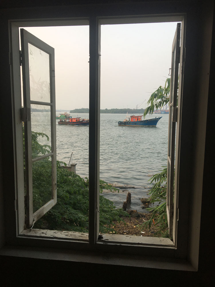 The view through an open window where Tom Burckhardt worked that looks out to the sea where two blue and red boats pass by