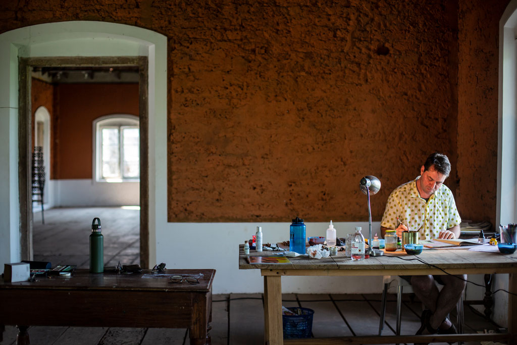 Tom Burckhardt works at a desk near a window in the expansive studio