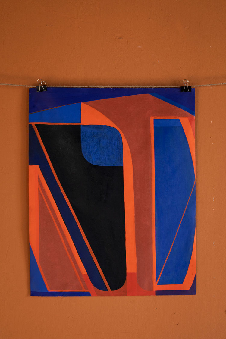 An abstract painting, featuring the red and blue color scheme, hangs from wire on a rugged wall
