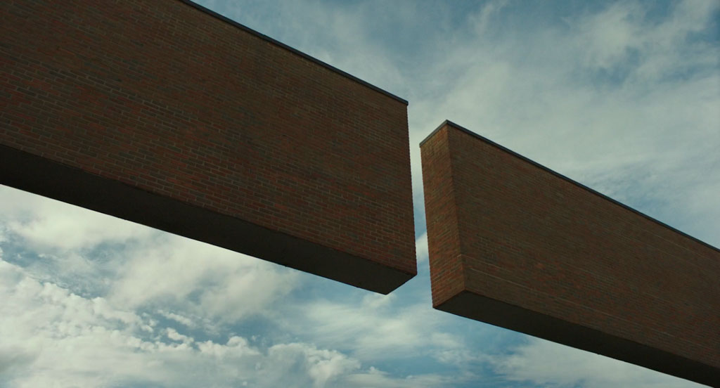 This close-up shot focuses on the two cantilevered arms that frame Columbus City Hall, designed by Edward Charles Bassett. The two brick arms reach toward each other, but do not touch. A sky filled with wispy clouds appears behind and between the two arms.