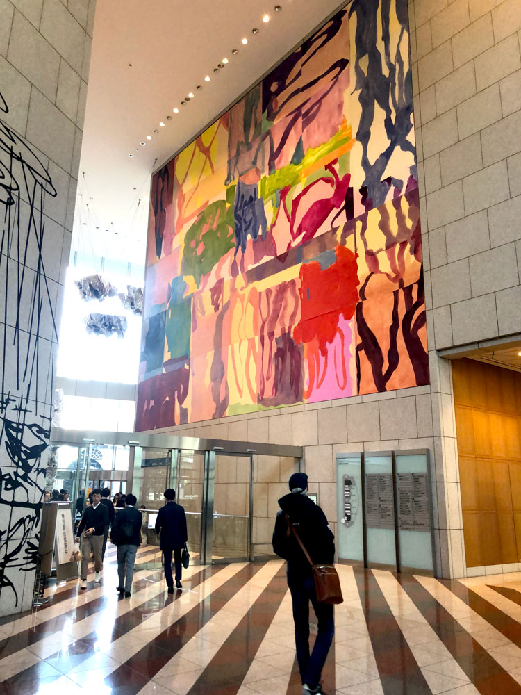 This photograph shows a large, brightly colored mural stretching across the entire wall of an interior plaza.