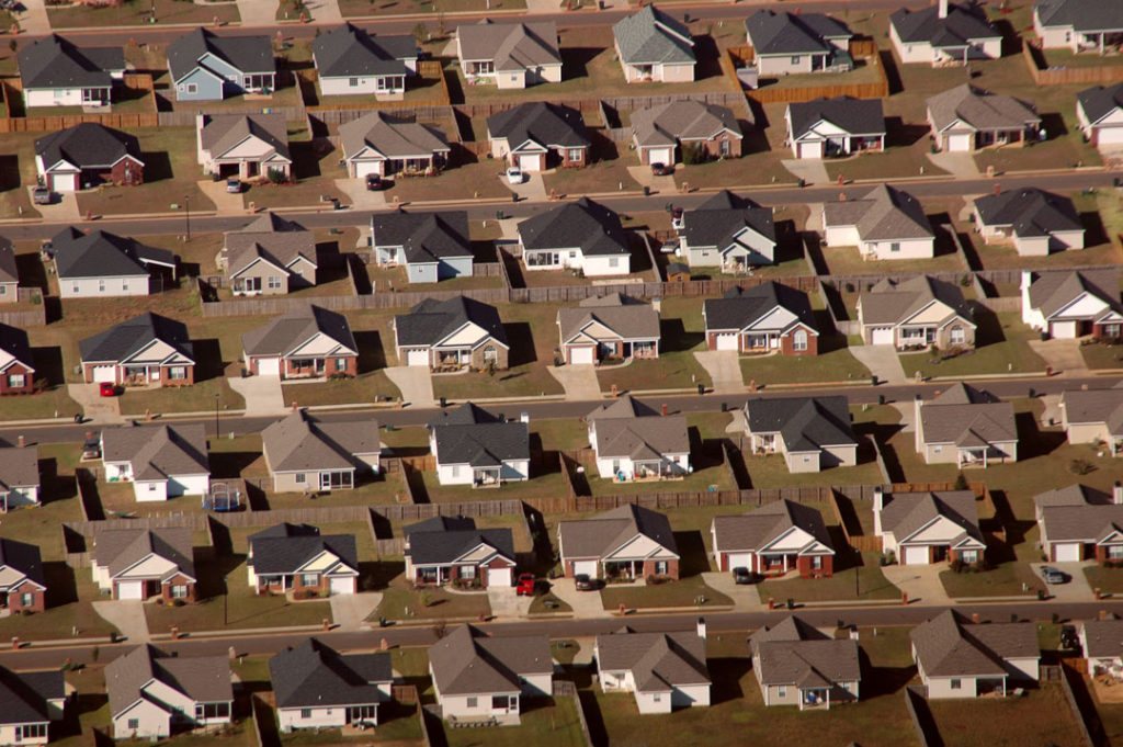 This birds eye view shows row after cramped row of nearly-identical suburban houses. None of the homes’ yards contain trees, clearly demonstrating the buildings' effects on climate change.