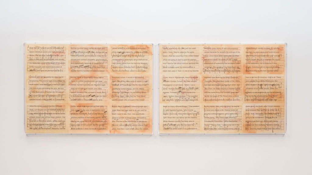 An installation view of Librettos: Manuel de Falla/Stokely Carmichael by Charles Gaines.  Two printed sheets showing annotated sheet music are presented side by side on a gallery wall.