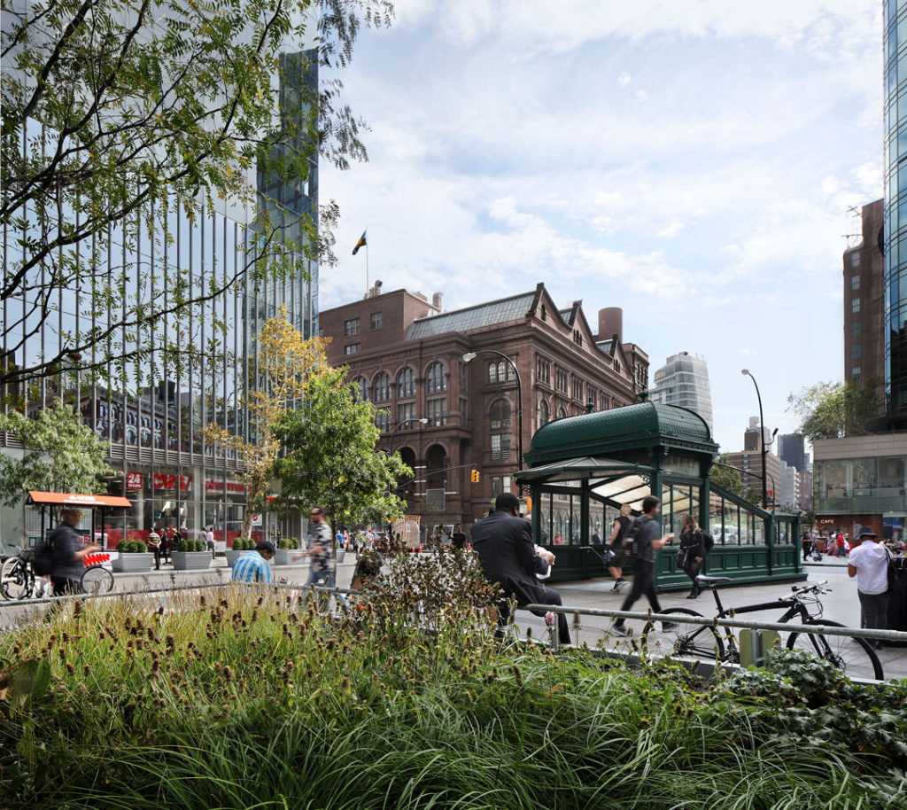A photograph of the exterior of the entrance to the Astor Place subway station.  A classic New York City subway entrance sits at the center of a busy plaza, surrounded by lush beds of flowers.  People sit, walk, and ride bikes.  Beyond the plaza is Cooper Union.