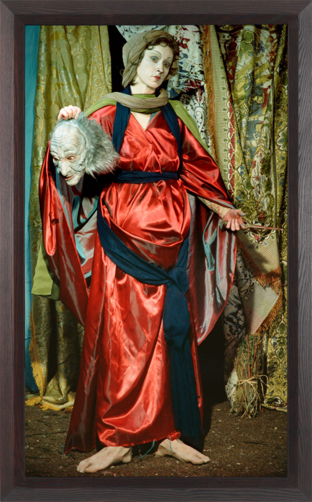 A photograph of Cindy Sherman in costume as an elegant and distinguished Judith.  In one hand, she displays a bloody knife, and in the other the grotesque head of Holofornes.