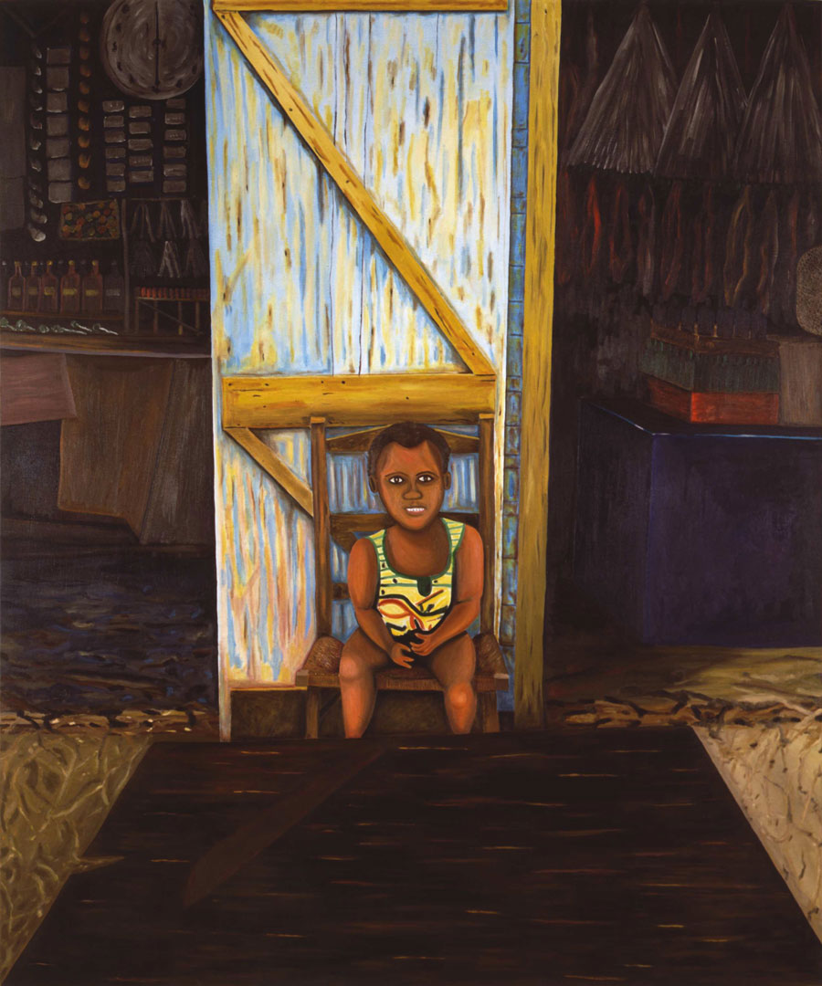 A smiling young boy sits in a chair in a workshop or store.