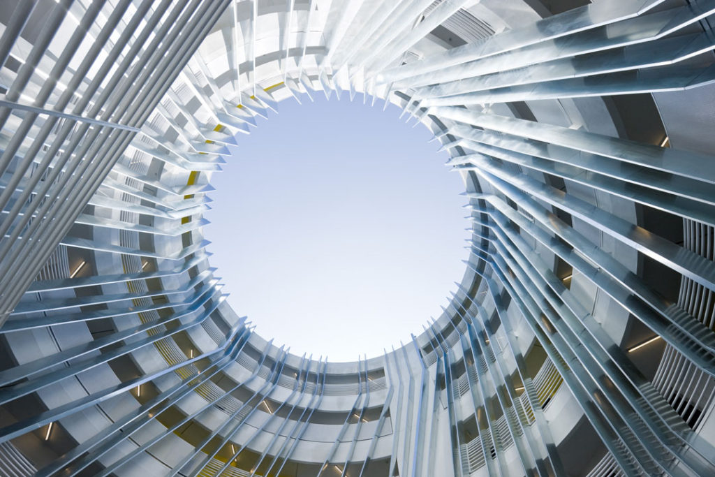 The interior courtyard of the New Carver Apartments, shot from ground level, looking straight up to the open-air.  The circular design of the building forms a spiral that frames the sky.
