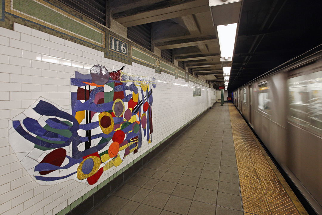 A view of Robert Blackburn’s glass mosaic work In Everything There Is a Season, installed on the platform wall of the 116th Street subway station in Harlem. The photo captures the movement of a train through the station, and the vibrant multicolored tiles used in Blackburn’s abstract art evoke the lively and diverse neighborhood above.